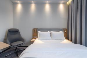 ein Hotelzimmer mit einem Bett und einem Stuhl in der Unterkunft Holiday Inn Express Munich Airport - Erding, an IHG Hotel in Erding