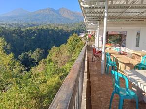 a balcony with blue chairs and tables and mountains at JABAAL GUEST HOUSE and RESTO in Senaru