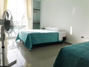 1 dormitorio blanco con 1 cama y ventilador en Hotel Guest House Inkayacu-Paracas, en Paracas