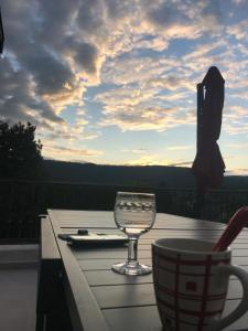 a table with a wine glass and a cup on a balcony at Longue Vue en Arbois in Arbois