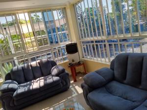 een woonkamer met 2 stoelen en een bank bij ODELIA GARDENS HOTEL-Kisumu CITY in Kibos