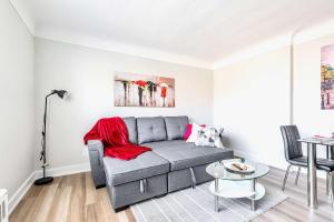 een woonkamer met een grijze bank en een tafel bij Corktown Hamilton - Modern Apartment in Hamilton