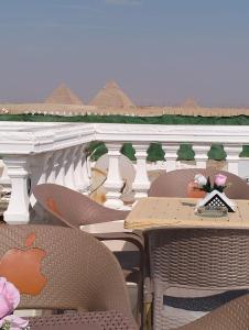 un patio esterno con tavoli e sedie su un balcone di Pyramids High View Inn a Giza