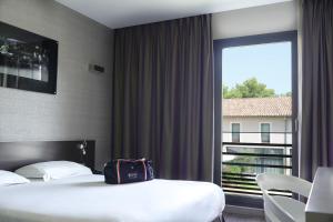 a hotel room with two beds and a large window at Grand Prix Hôtel & Restaurant in Le Castellet