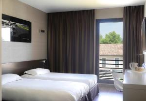 a hotel room with two beds and a window at Grand Prix Hôtel & Restaurant in Le Castellet