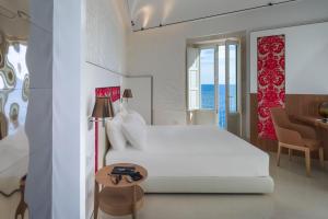 ein weißes Schlafzimmer mit einem weißen Bett und einem Tisch in der Unterkunft Maniace Boutique Hotel Ortigia | UNA Esperienze in Syrakus