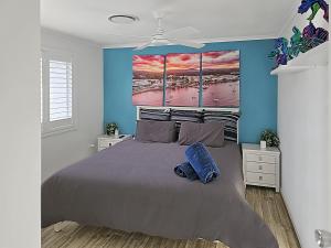 a bedroom with a large bed with a blue wall at Skyes Beach House - The entertainer - Pet Friendly in Malua Bay