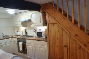 Llanbedr-y-cenninYr Hen Efail Cosy 1 bedroom Cottage, with fireplace and garden的厨房配有白色橱柜和木制楼梯。