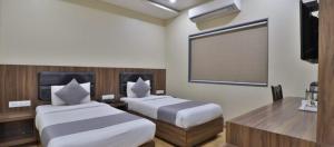 um quarto de hotel com duas camas e um ecrã de projecção em Hotel Limra Vadodara em Vadodara