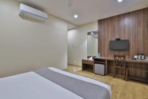 um quarto de hotel com uma cama e uma televisão em Hotel Limra Vadodara em Vadodara