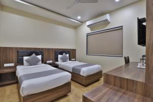 um quarto com 2 camas e uma televisão de ecrã plano em Hotel Limra Vadodara em Vadodara