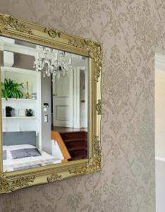 een gouden spiegel aan een muur met een slaapkamer bij B&B de Notaris in Assen