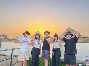 カイロにあるLocanda pyramids viewの夕日の前に立つ集団