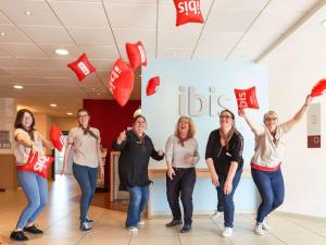 un grupo de personas de pie en un vestíbulo con banderas rojas en ibis Cholet, en Cholet