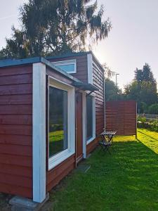 eine kleine Hütte mit einem Fenster und einem Stuhl im Gras in der Unterkunft Gästehaus Maria Rast in Suderburg