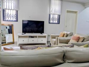 ein Wohnzimmer mit Sofas und einem Flachbild-TV in der Unterkunft Beautiful Home - 2 Double Rooms in Accra