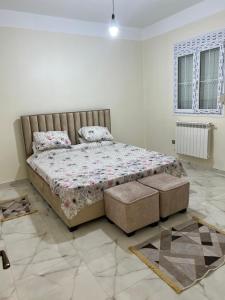 ein Schlafzimmer mit einem Bett und einer Ottomane in einem Zimmer in der Unterkunft Loft19 in Sétif