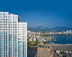 un edificio blanco alto junto a un cuerpo de agua en The Hotel Sokcho by Best Western Signature Collection, en Sokcho