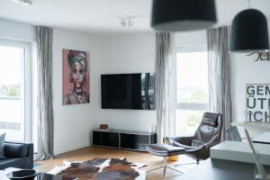 een woonkamer met een bank en een tv bij Prime Park Penthouse Aschaffenburg in Aschaffenburg