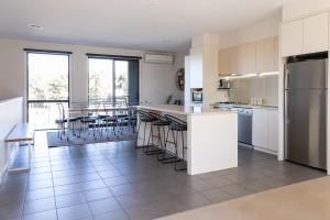 a kitchen with white cabinets and a kitchen island with bar stools at Torquay Golf Retreats - Pool, Beach, Tennis, Golf in Torquay