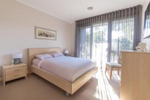 a bedroom with a bed and a large window at Torquay Golf Retreats - Pool, Beach, Tennis, Golf in Torquay