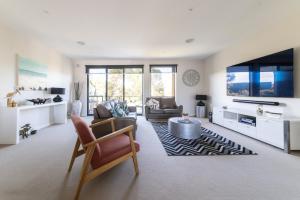 a living room with a large tv and a couch at Torquay Golf Retreats - Pool, Beach, Tennis, Golf in Torquay