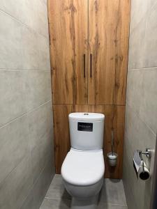 La salle de bains est pourvue de toilettes et d'une porte en bois. dans l'établissement Однокомнатная квартира, à Öskemen