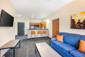 Best Western Lubbock West Inn & Suites في لوبوك: غرفة معيشة مع أريكة زرقاء ومطبخ