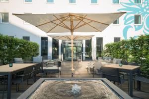 patio ze stołami, parasolem i fontanną w obiekcie Motel One Hamburg Airport w mieście Hamburg