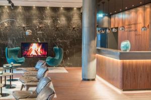 hol z krzesłami, kominkiem i telewizorem w obiekcie Motel One Hamburg Airport w mieście Hamburg