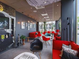 una habitación con sillas y mesas rojas y un bar en ibis Lyon Carre De Soie, en Vaulx-en-Velin