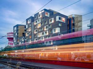 un edificio con un tren pasando delante de él en ibis Lyon Carre De Soie, en Vaulx-en-Velin