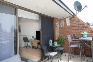 einen Balkon mit einem Tisch, Stühlen und einer Ziegelwand in der Unterkunft Joy's Hideaway in Terrigal