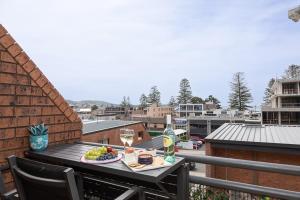 einen Tisch mit einem Teller Essen und Wein auf dem Balkon in der Unterkunft Joy's Hideaway in Terrigal