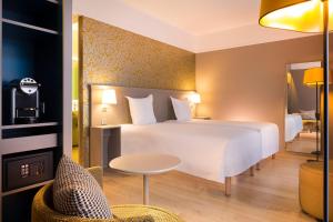 Habitación de hotel con cama blanca y mesa en Oceania Le Jura Dijon, en Dijon