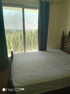 a bedroom with a bed and a large window at Mount View Hotel Skardu in Skardu