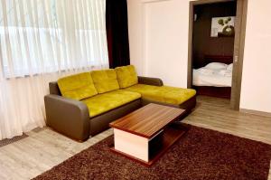 a living room with a yellow couch and a table at Silver Mountain, Poiana Brasov - Forest Crib in Braşov