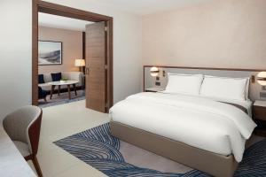 um quarto com uma grande cama branca e uma secretária em The Westin Saraya Aqaba Resort & Spa em Aqaba