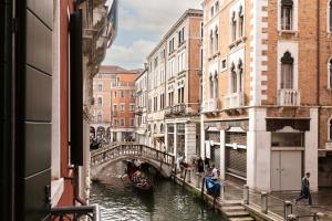 a canal in a city with a bridge and a boat at Numa Venice Palazzo Orseolo in Venice