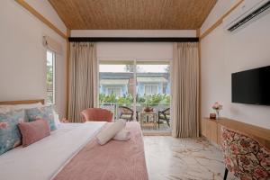 1 dormitorio con cama grande y ventana grande en Miia Bella Beach Cottage Resort, en Baga