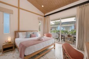 1 dormitorio con cama y ventana grande en Miia Bella Beach Cottage Resort, en Baga