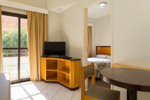 ein Hotelzimmer mit einem TV, einem Tisch und einem Bett in der Unterkunft Golden Suíte Hotel in Campinas