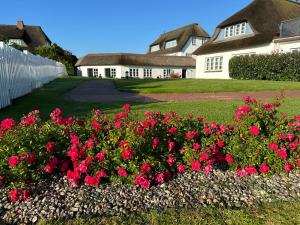 ein Bett mit roten Blumen vor einem Haus in der Unterkunft Haus Amanda in Norddorf