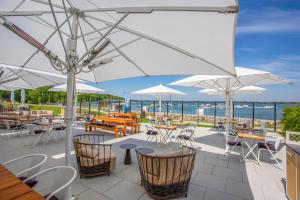 un patio con tavoli, sedie e ombrelloni bianchi di Maremüritz Yachthafen Resort a Waren