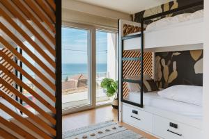 - une chambre avec des lits superposés et un balcon donnant sur l'océan dans l'établissement The Salty Pelican Yoga & Surf Retreat, à Ericeira