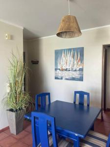 a blue dining room table with blue chairs and a painting of sailboats at T1 Vista Marina de Vilamoura in Vilamoura