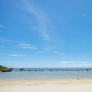 a beach with the ocean and rocks in the distance at Scallop Beach Condominium in Onna