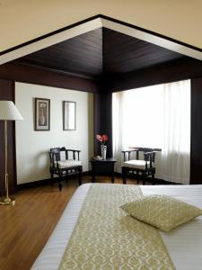 um quarto com uma cama grande e um quarto com cadeiras em The Gateway Hotel Beach Road, Calicut em Calecute