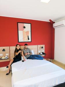 a man and a woman sitting on a bed at Rua Hoteles Talara in Talara