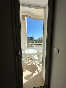 una porta che conduce a un balcone con tavolo e sedie di Luxueux appt jardin de Carthage a La Goulette (La Goletta)